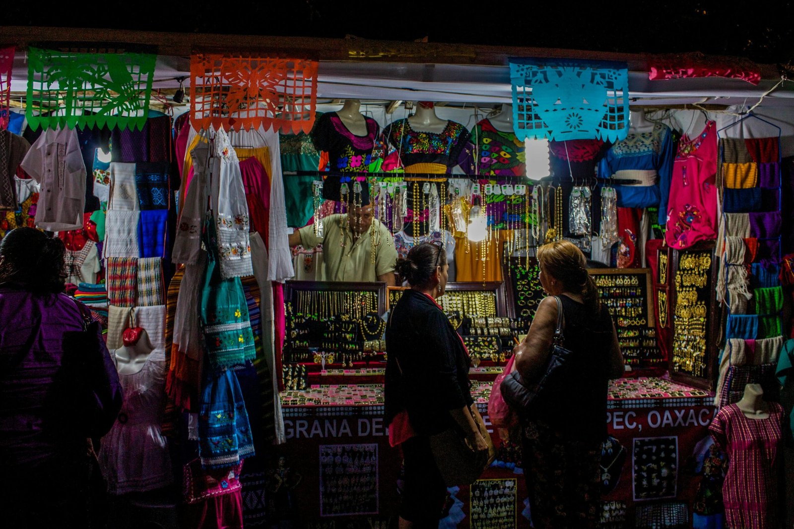 Carritos de madera repletos de artesanías coloridas y ropa bordada a mano en Oaxaca, mostrando el talento de los artesanos locales.
