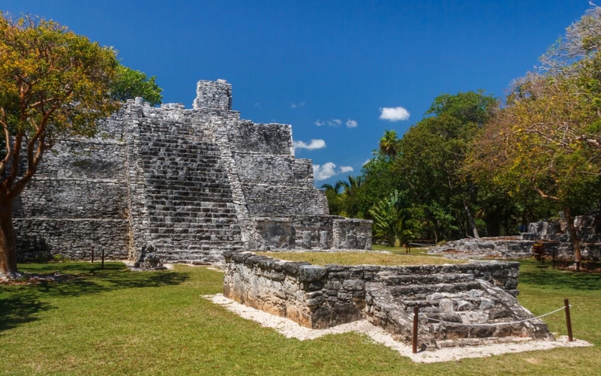 Destino de ecoturismo Pirámide principal El Castillo en la zona arqueológica El Meco, Cancún rodeado de árboles tropicales y naturaleza