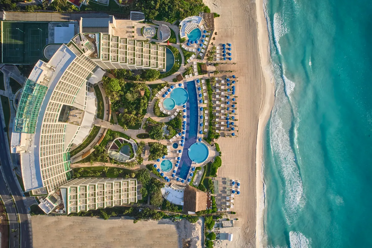 Vista aérea del Live Aqua Beach Resort Cancún, destacando su múltiples albercas y jardines tropicales frente al mar turquesa del Caribe