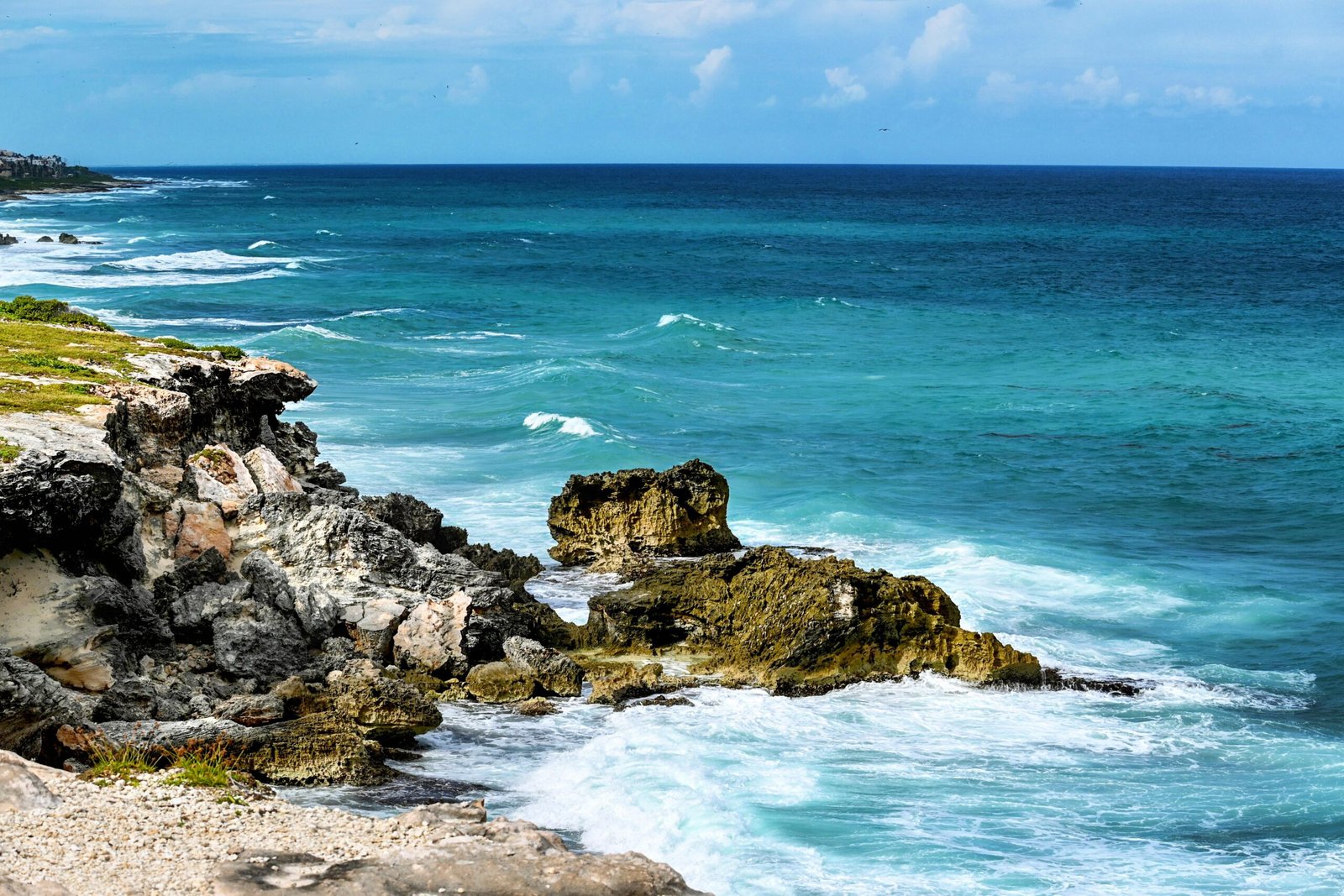 Fotografía de paisaje costero que muestra la Punta Sur de Isla Mujeres, México. Muestra tonalidades azules del mar Caribe y rocas.
