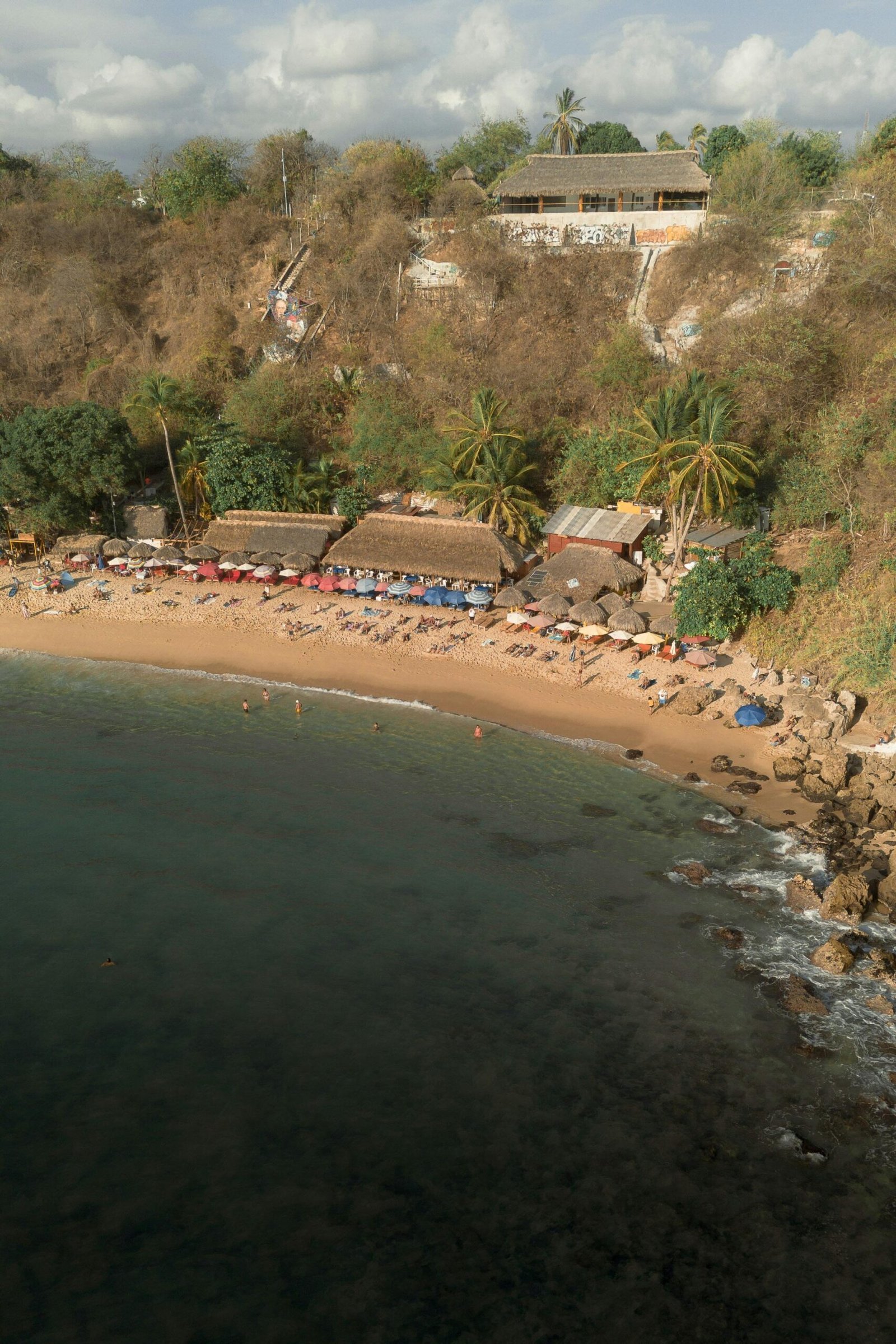 Vista de la playa en Puerto Escondido Oaxaca con palapas, arena dorada y mar azul en la costa del Pacífico mexicano, destino turísico tropical