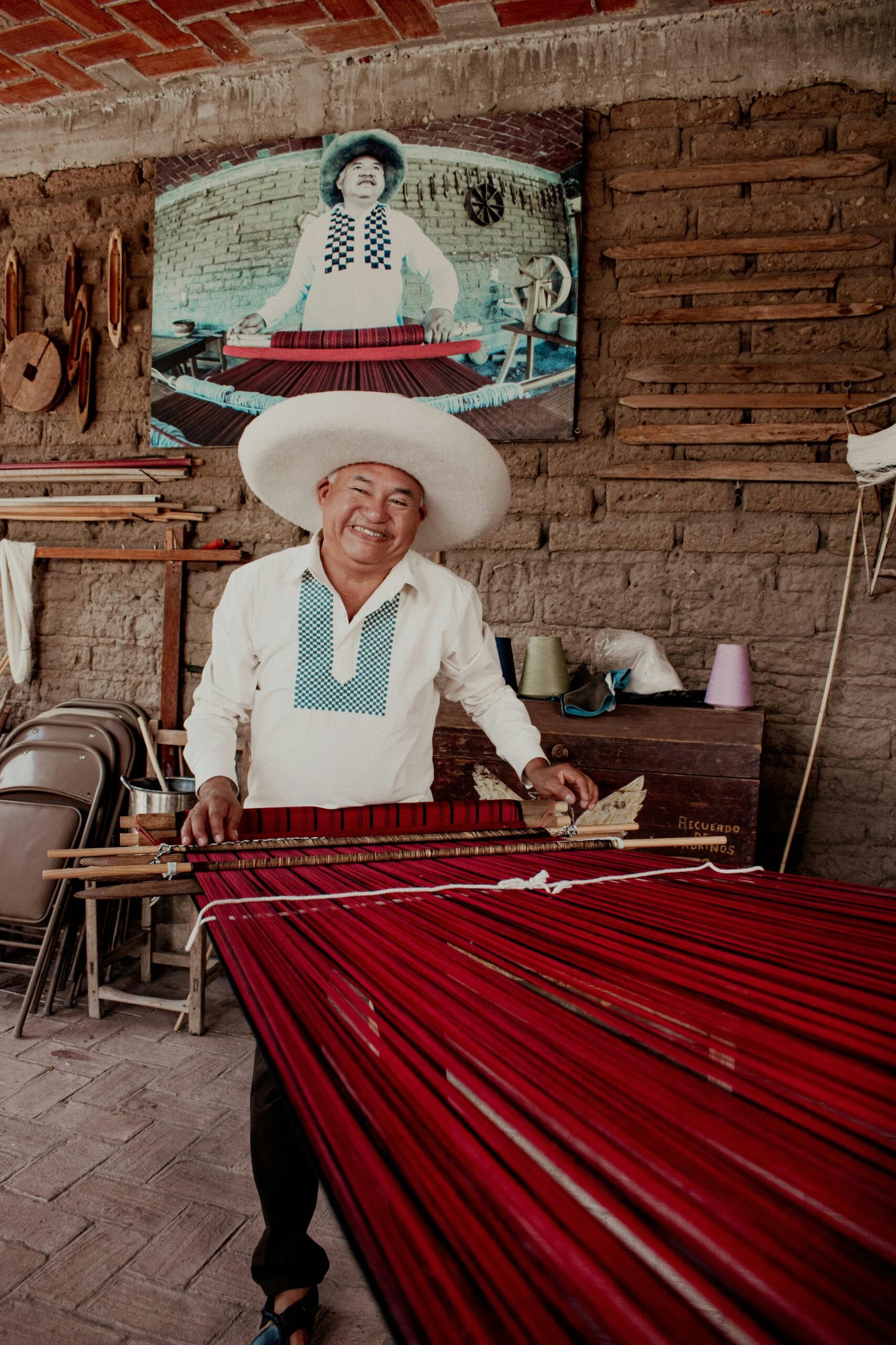 Artesano oaxaqueño tejiendo un tapete de lana rojo en un telar de pedal tradicional en taller de Oaxaca