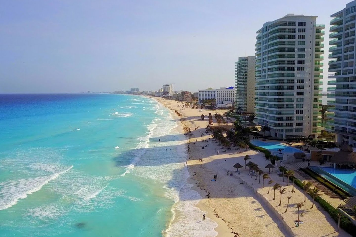 Vista panorámica de Playa Chac Mool en la Zona Hotelera de Cancún, con edificios altos, arena blanca y mar turquesa con olas