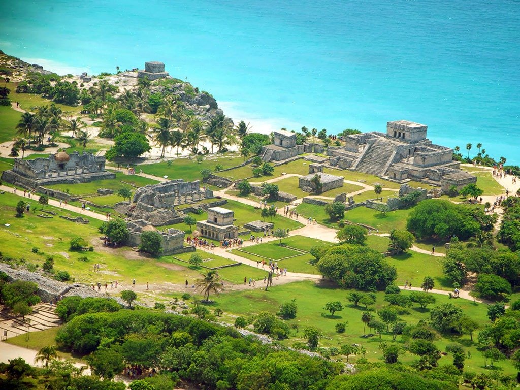 Zona arqueológica de Tulum en la Riviera Maya vista panorámica de ruinas y pirámides mayas junto al mar turquesa con turistas recorriendo el sitio