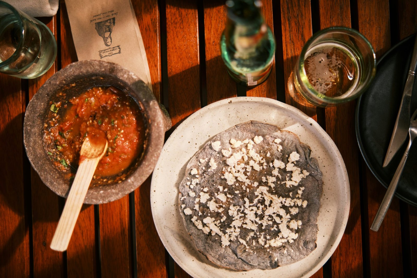 Tlayuda oaxaqueña con queso y salsa en molcajete sobre mesa de madera comida tradicional mexicana